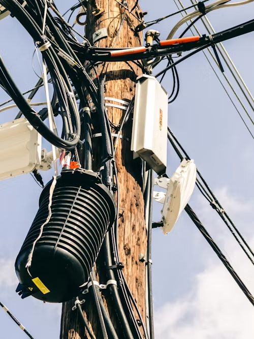 Network equipment and cabling mounted on a utility pole against a clear sky