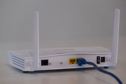 A white router on a desk with a network cable connected